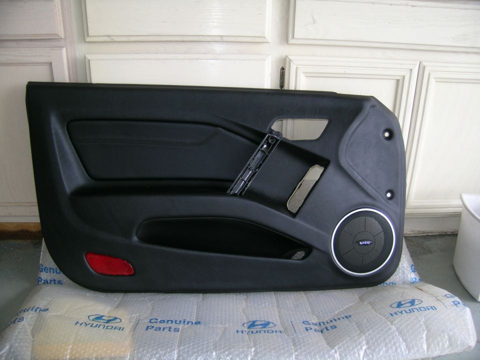 Black car door panel with speaker grille on Hyundai parts wrap in a garage