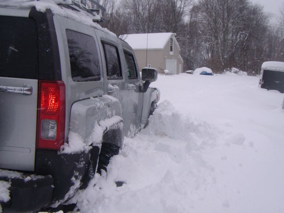 Silver SUV partially buried in snow, rear taillight visible