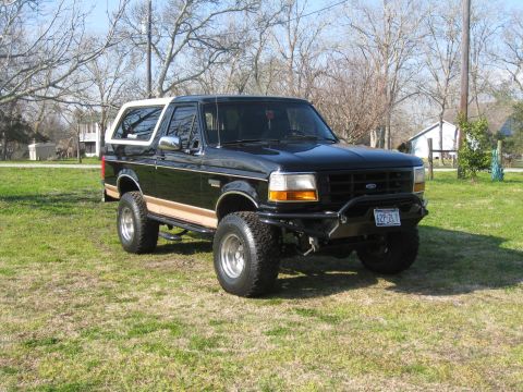 1994 Ford Bronco - This lifted 1994 Ford Bronco features a two-tone paint scheme with a tan stripe and a white removable top.