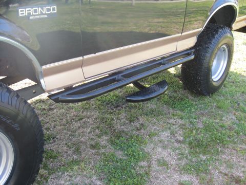 1994 Ford Bronco - This image focuses on the side of a 1994 Ford Bronco, highlighting its running boards and off-road tires.