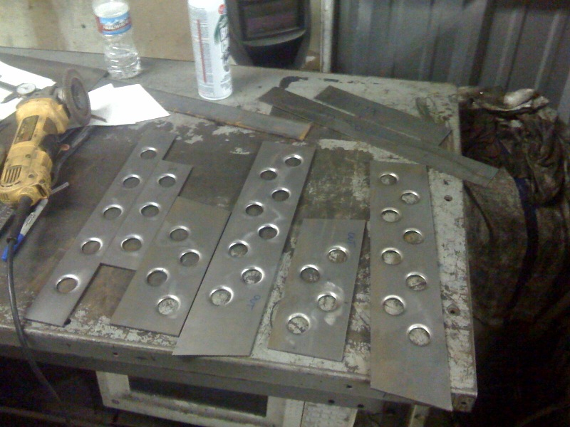 Metal plates with rows of holes and an angle grinder on a workbench