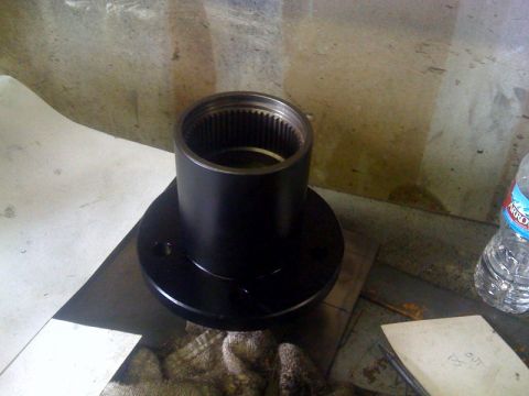 1994 Jeep YJ - A black metal automotive part with internal splines sits on a workbench next to a water bottle.