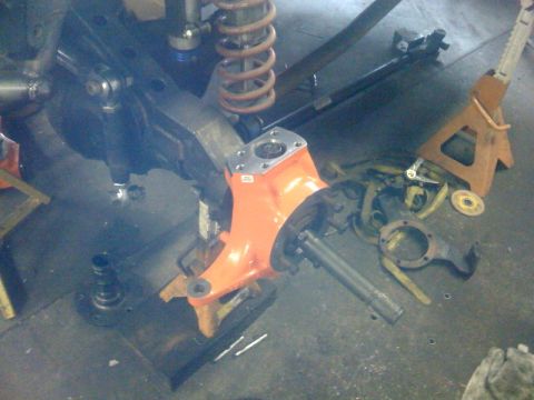 1994 Jeep YJ - Close-up view of an orange-painted axle housing and various suspension components, likely during a repair or modification.