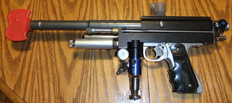 Paintball marker with red handle on barrel, silver and blue air tank, and black grip