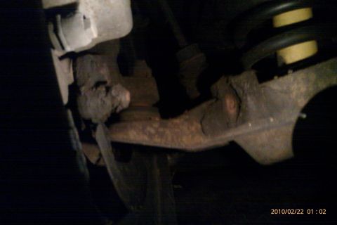 2000 Mercury Grand Marquis - Undercarriage view of aged suspension components, showing rust and wear on a vehicle part.