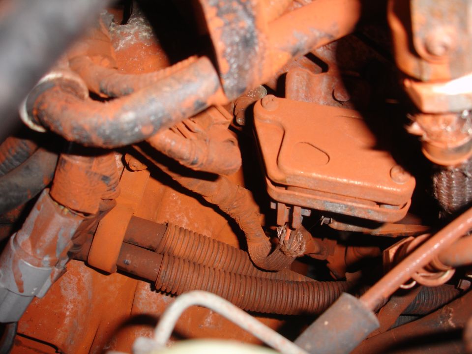 Engine bay components and wiring coated in orange-red dust, close-up