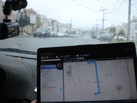 1989 Ford Taurus - Laptop shows GPS navigation on a rainy day in San Francisco, with other vehicles visible on the street.