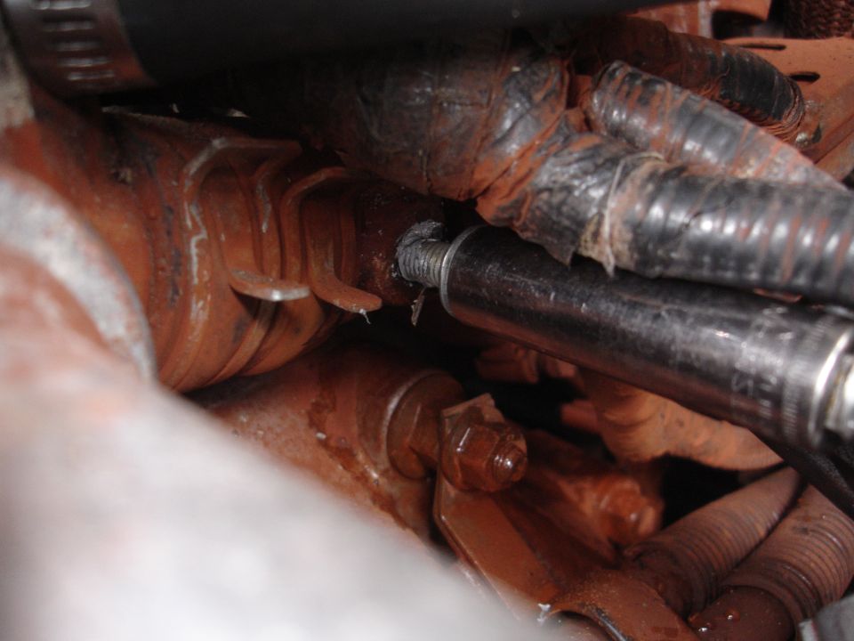 Rusty engine-bay exhaust manifold, stud and hoses