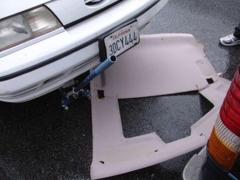 1989 Ford Taurus - A detached headliner lies on the ground near the front of a 1989 Ford Taurus.