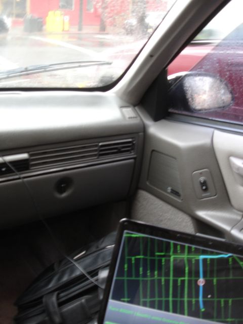 1989 Ford Taurus - Interior view of a 1989 Ford Taurus with a laptop and briefcase, showing a rainy day outside.