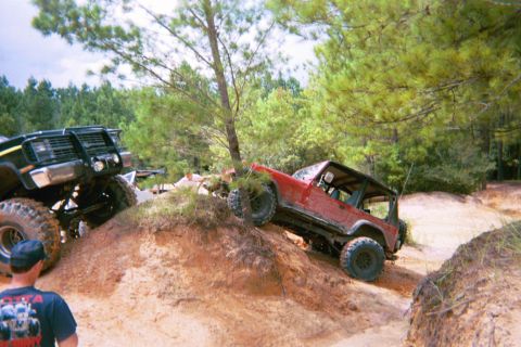 1985 Ford Bronco - Two off-road vehicles navigate a challenging dirt terrain during an outdoor excursion.