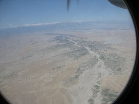 2003 Jeep Wrangler - An aerial perspective captures a winding river valley leading towards distant, snow-capped mountains, viewed through an aircraft's porthole.