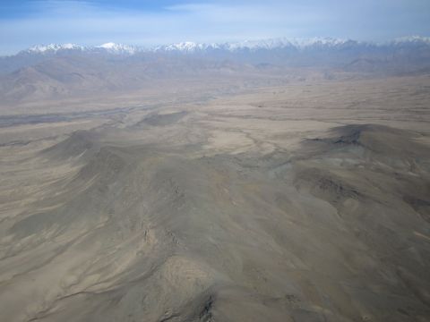 2003 Jeep Wrangler - An aerial view shows a vast, dry, mountainous terrain under a hazy blue sky.