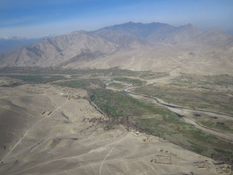 2003 Jeep Wrangler - Expansive desert terrain with mountains, a river, and ancient structures under a clear blue sky.