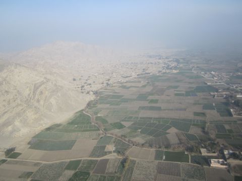2003 Jeep Wrangler - An aerial perspective captures a vast landscape of cultivated fields stretching towards a distant town against a mountainous backdrop.