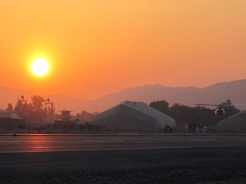 2003 Jeep Wrangler - A helicopter flies over an airport tarmac during a vibrant sunset, with mountains in the background.