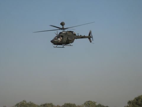 2003 Jeep Wrangler - A military helicopter is captured in mid-flight, with a hazy landscape visible below.