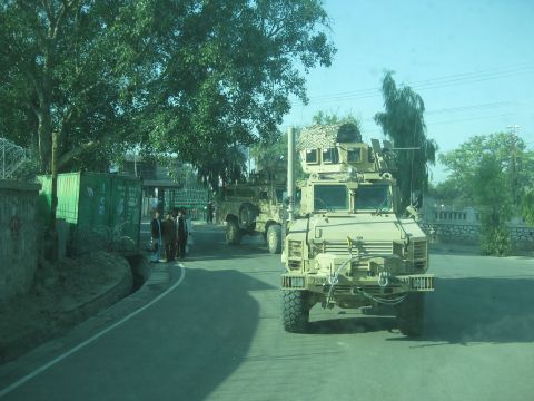 2003 Jeep Wrangler - Military vehicles are seen on a road in Afghanistan, with people standing nearby.