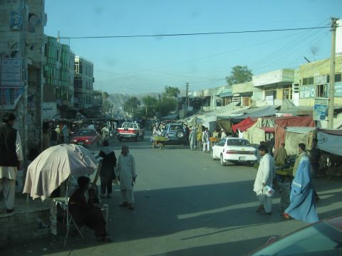 2003 Jeep Wrangler - A bustling street market scene unfolds with various vehicles and people navigating the thoroughfare.