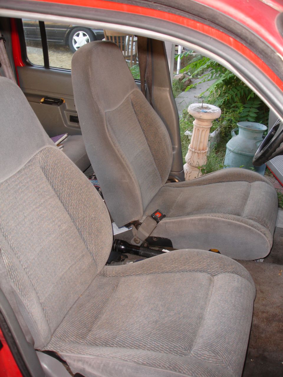 front seats of a car, gray fabric, seatbelts visible