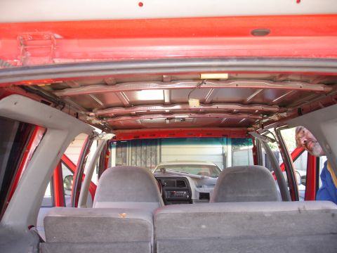 1992 Ford Explorer - The interior of a red SUV shows exposed ceiling supports and gray seats, with another vehicle visible outside.