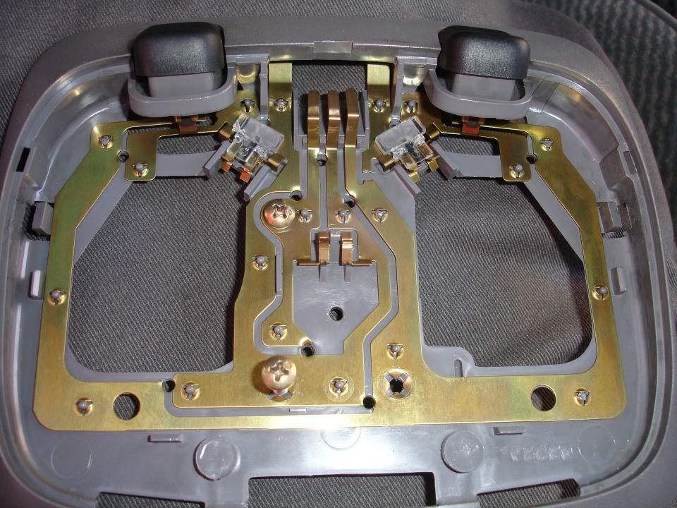 Interior light assembly with two black buttons, brass contacts, and gray plastic housing