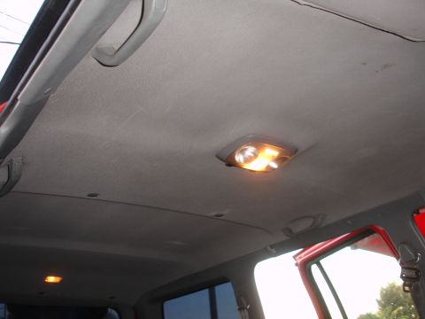 1992 Ford Explorer - The interior ceiling of a vehicle features two dome lights and gray grab handles.