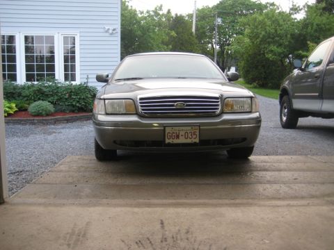 1999 Ford Crown Victoria - Front view of a silver 1999 Ford Crown Victoria, parked next to a pickup truck.