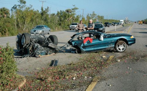 1978 Ford Mustang II - Two vehicles are stopped on the side of a road, with one appearing to be a truck towing another vehicle.
