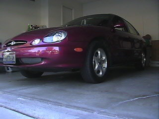1999 Ford Taurus - Maroon 1999 Ford Taurus sedan parked in a garage, showing its front 3/4 view.