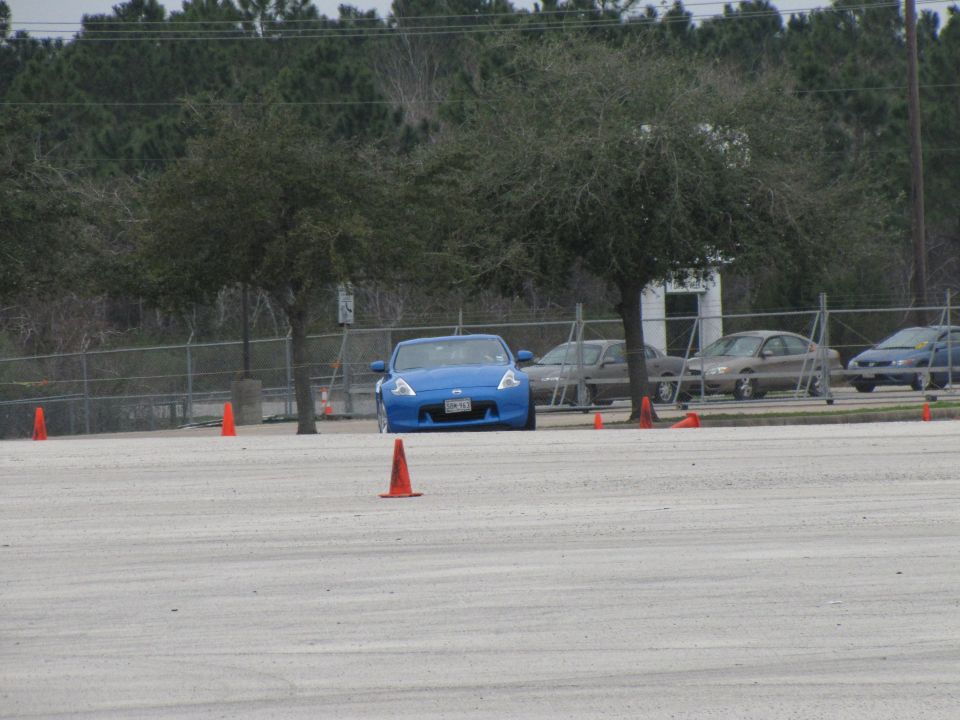 Blue sports car with orange cones on a paved lot