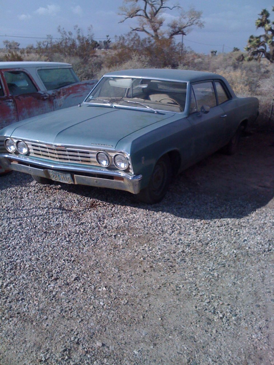 1966 Chevrolet Chevelle sedan, light blue, parked next to a red truck