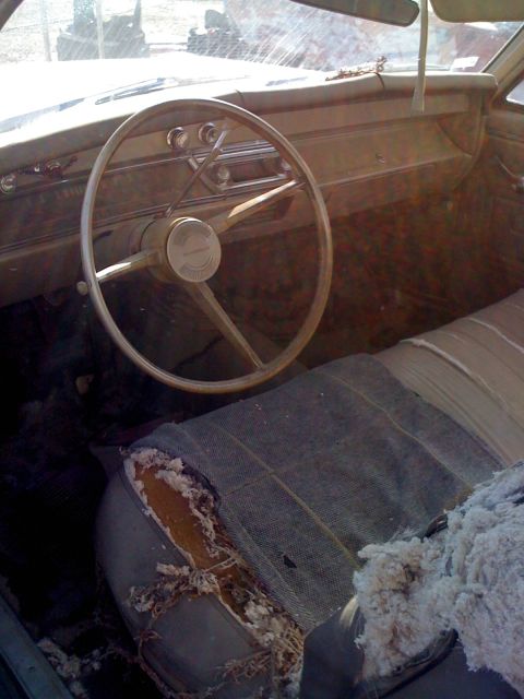 1968 Ford Mustang - The interior of a car shows a worn driver's seat and dashboard with a classic steering wheel.