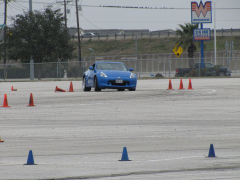 2003 Mazda Protege - Blue Nissan 370Z navigates a cone course on a paved track.