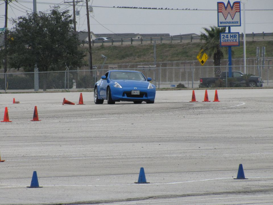 Blue Nissan 370Z driving on a track with orange and blue cones
