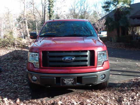 2009 Ford F-150 - The front grille of a red Ford F-150 truck is visible, with a license plate below.
