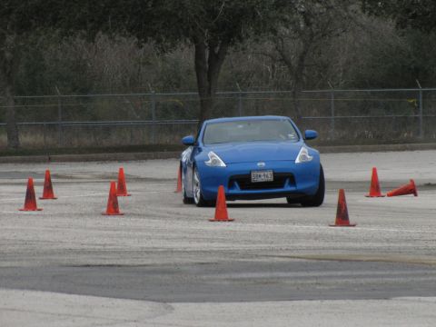 2003 Mazda Protege - A blue sports car maneuvers through an autocross course marked by orange traffic cones.