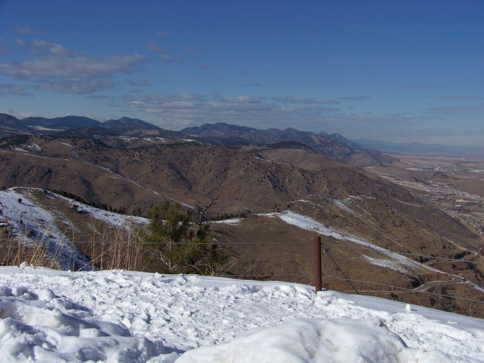snowy mountain landscape with distant town and blue sky