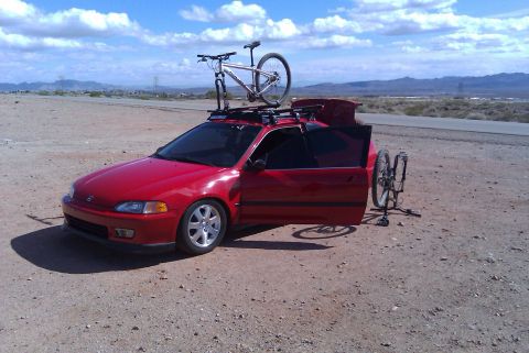 1993 Honda Civic - A red 1992 Honda Civic hatchback is parked on a dirt road with two bicycles, one on the roof rack and another leaning against the open pass…
