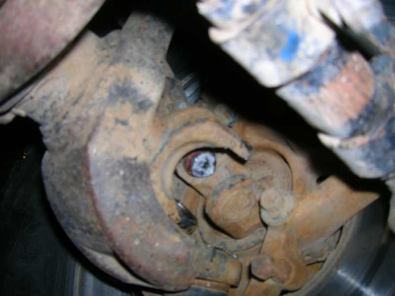 Close-up of a heavily rusted suspension component, possibly from a vehicle's axle or brake assembly