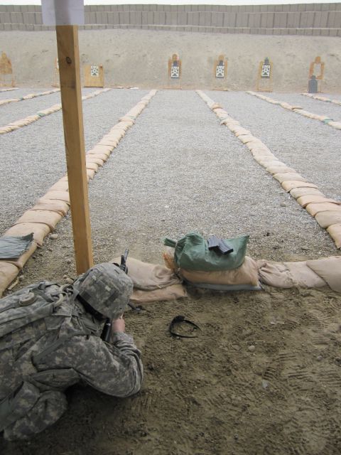 2003 Jeep Wrangler - A soldier lies prone at a shooting range, aiming at targets downrange. Sandbags line the lanes.