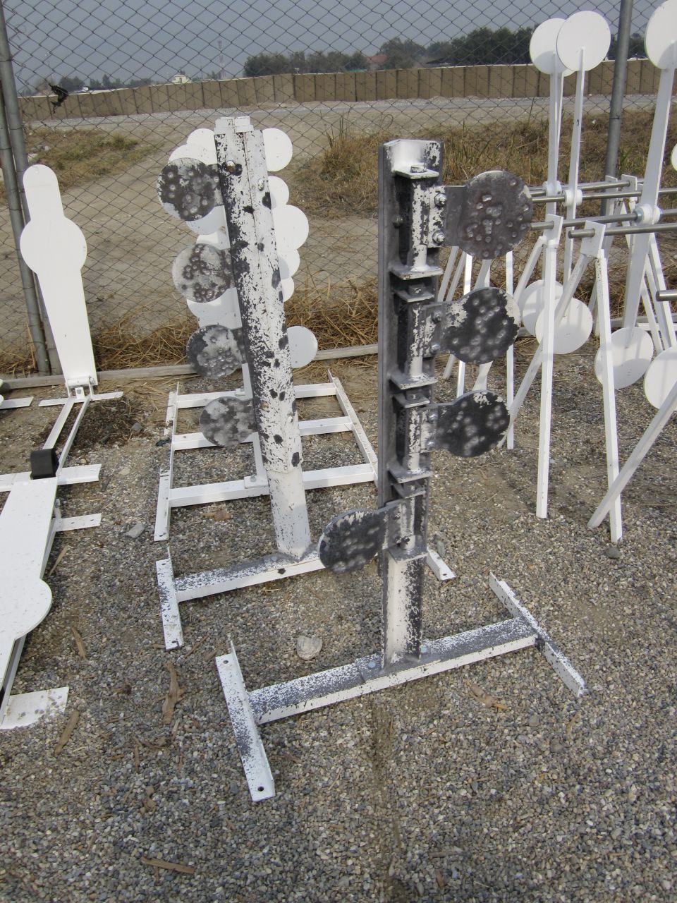 Several metal shooting targets, some with multiple spinning plates, are set up on stands