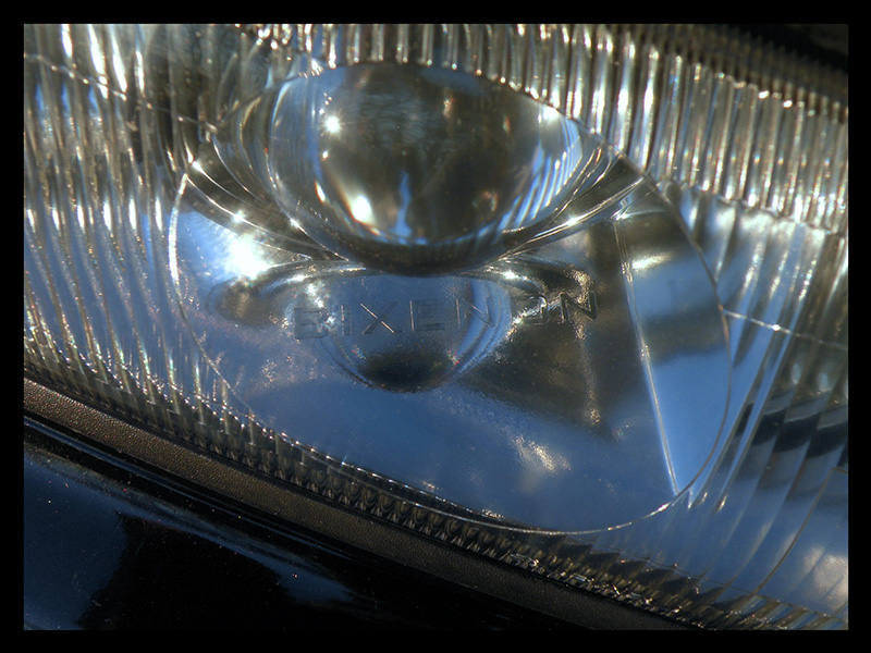 Close-up of a projector headlight lens with BIXENON text molded into the glass