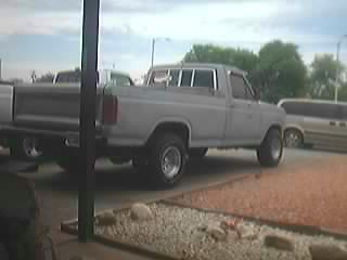 1985 Ford F-150 - A gray Ford F-150 pickup truck is parked outside with a SuperMotors logo visible at the bottom right.