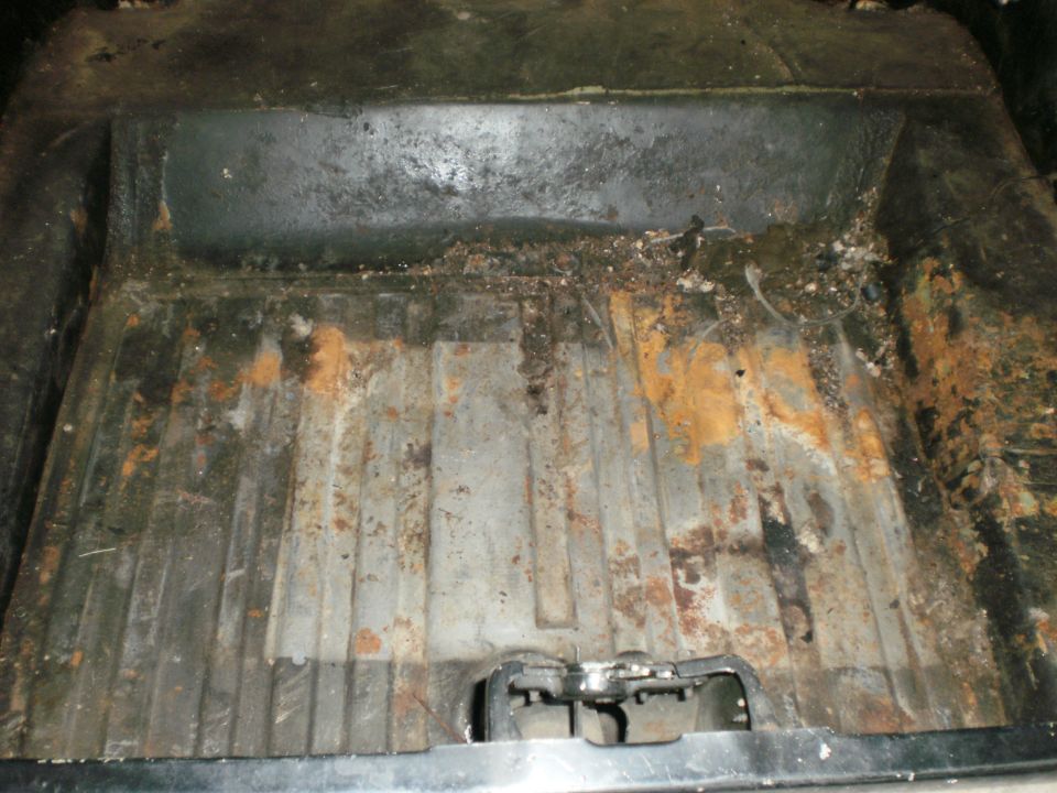 Rusty trunk interior with visible water damage and corrosion
