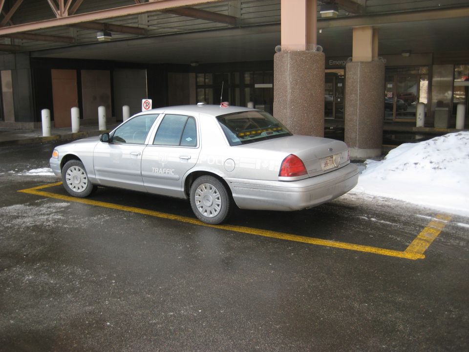 Silver sedan parked in a yellow-lined spot, text on door says 'TRAFFIC'. Looks like a police or government vehicle
