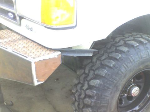 1989 Ford Bronco - Close-up of the front corner of a Ford truck, showing a custom bumper and tire. The year is estimated to be around 1980.