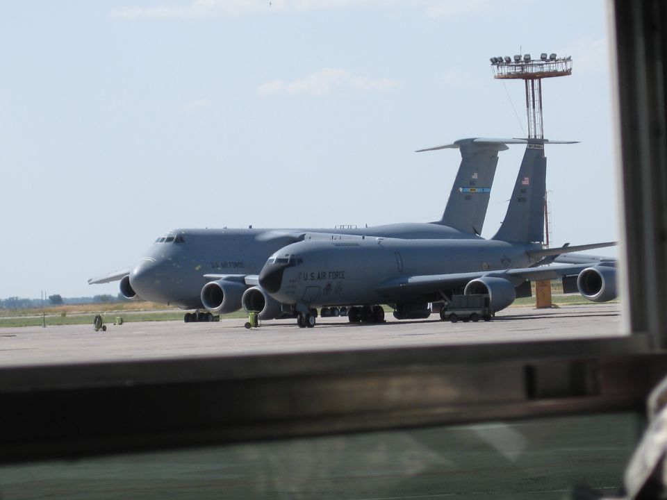Two gray US Air Force refueling tanker aircraft parked on an airfield, one behind the other