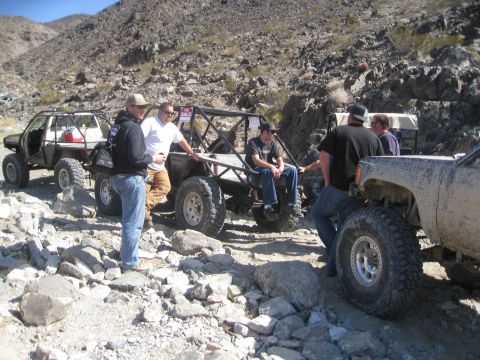 1994 Jeep YJ - Modified off-road vehicles and people in a rocky desert landscape. One vehicle is marked for sale.