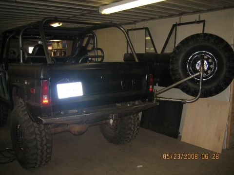 1967 Ford Mustang - Rear view of a black SUV, possibly a Ford Bronco, with a custom external spare tire carrier and roll cage installed.